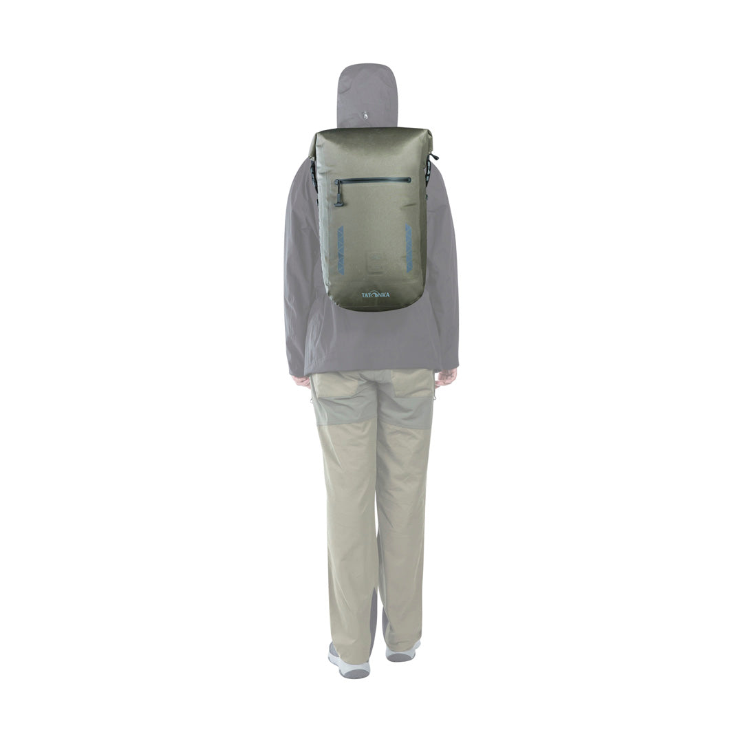 Back view of person using the 25 litre Tatonka Torrent roll-top backpack with the roll top secured to the sides of the pack - Stone Grey Olive