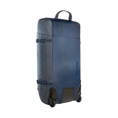 Front three-quarter view of 105 litre Tatonka Duffel Roller with grab handle on top, compression straps at side and wheels on facing bottom edge - Navy