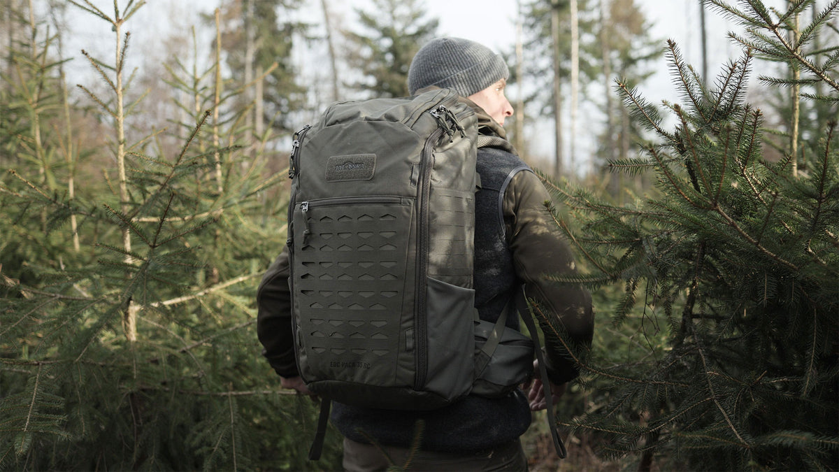 Rear view of man carrying a Tatonka EDC pack with MOLLE panels and side pockets - Olive