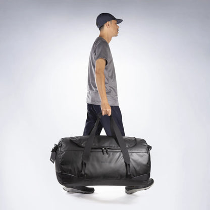 Being carried by the handles of the Tatonka Basic Barrel 85 L in matte black | TADI.6982.408